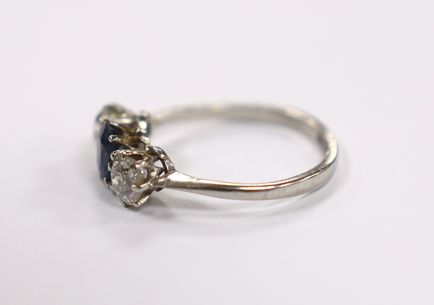 An early to mid 20th century white metal (stamped plat), single stone sapphire and two stone diamond set ring, size M, gross weight 2.7 grams.